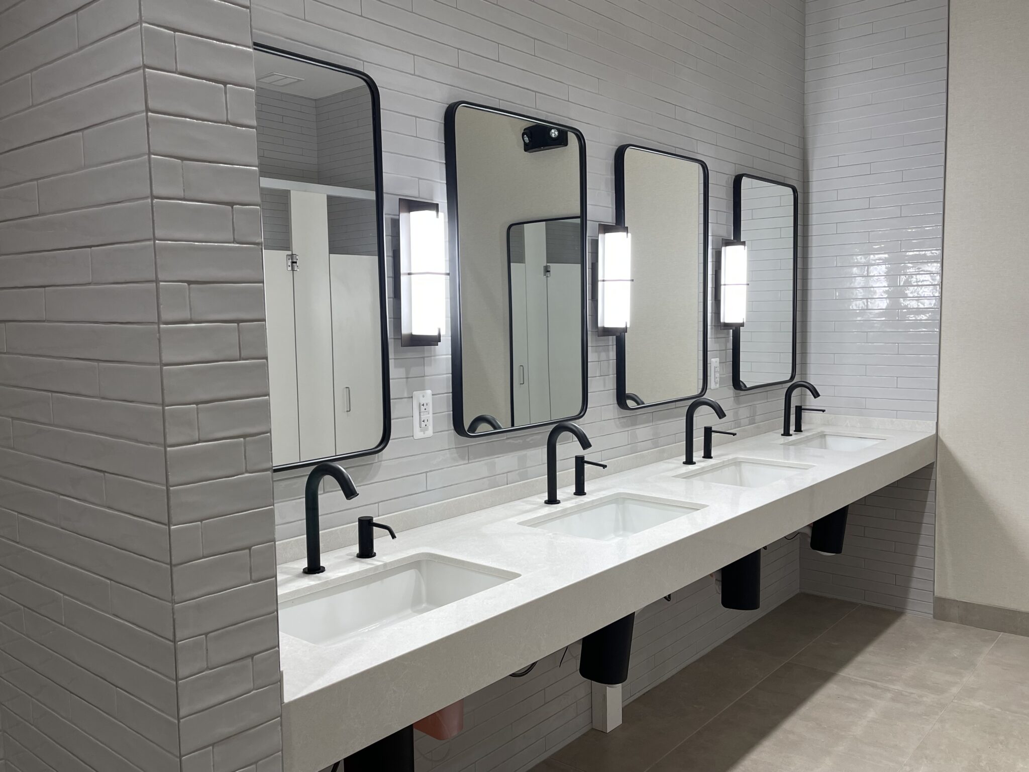 A bathroom with four sinks and mirrors in it.