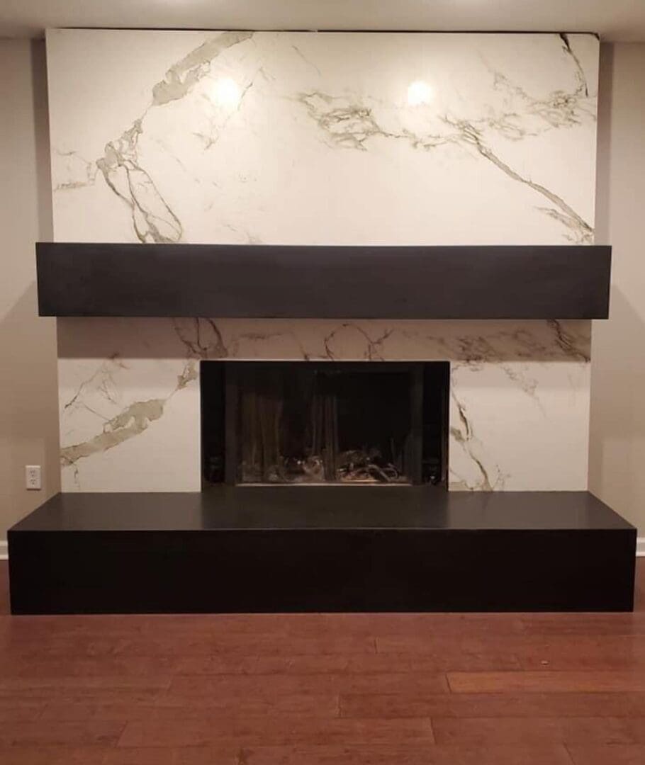 A fireplace with marble walls and a black mantle.