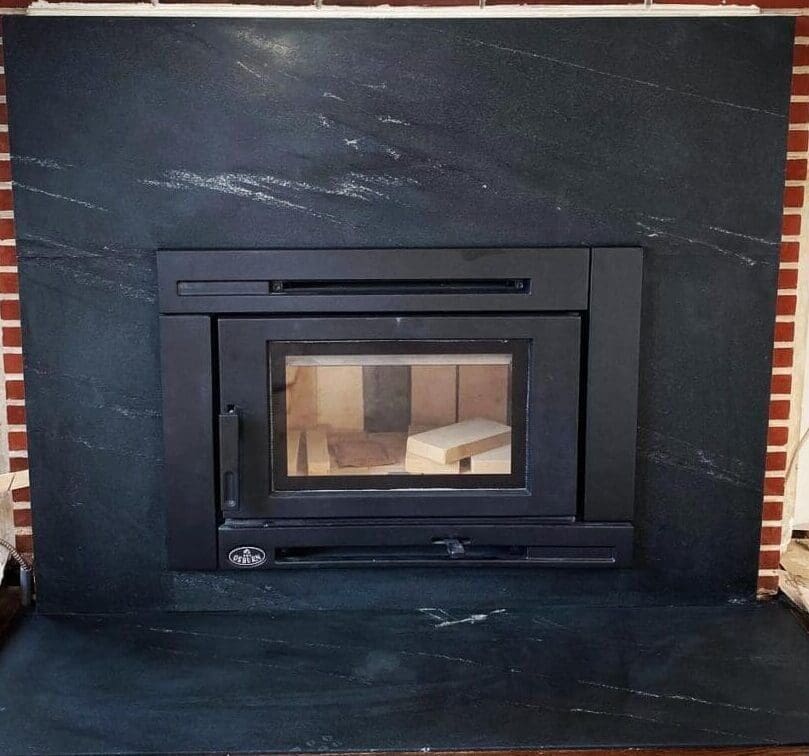 A fireplace with a black stone surround and a glass door.