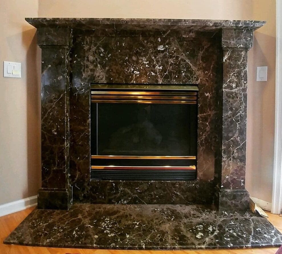 A fireplace with marble surround and black trim.