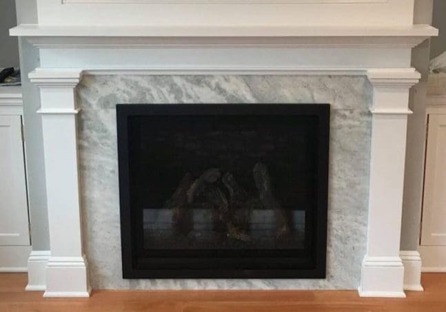 A fireplace with marble surround and white trim.