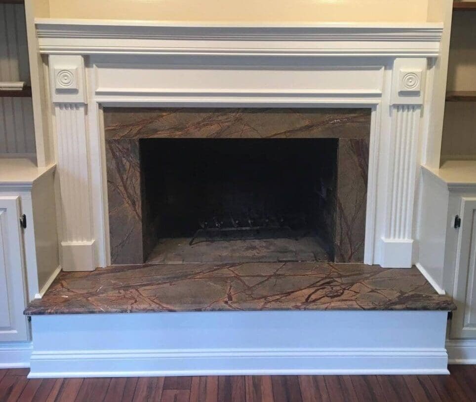A fireplace with marble surround and white mantel.