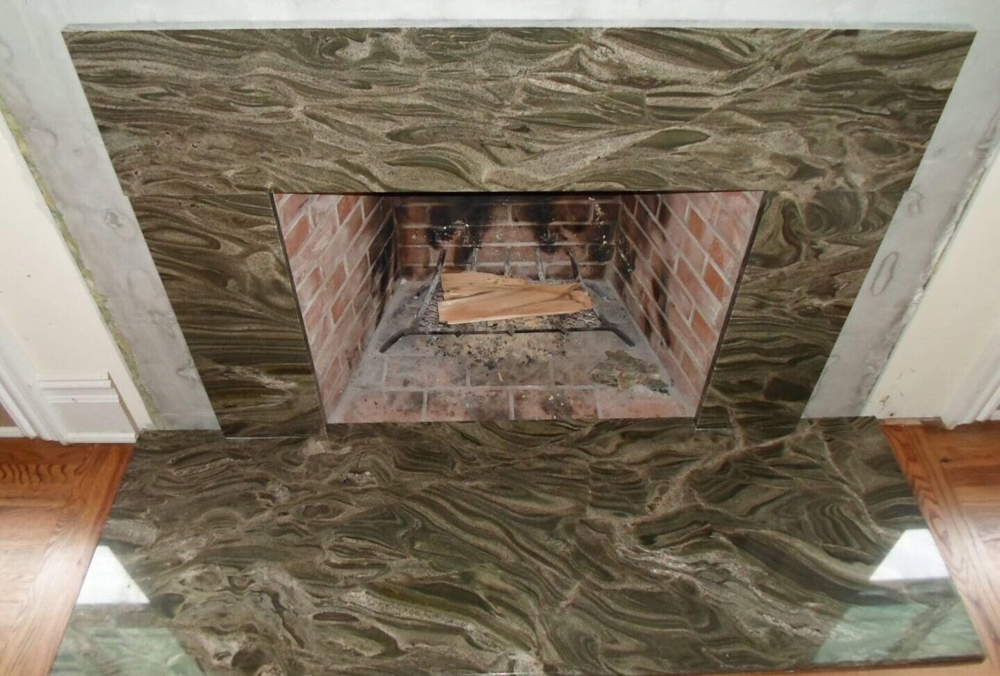 A fireplace with marble tile and wood in the center.