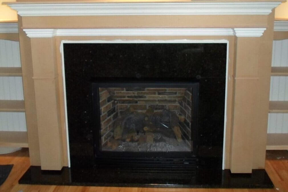 A fireplace with black marble surround and white trim.