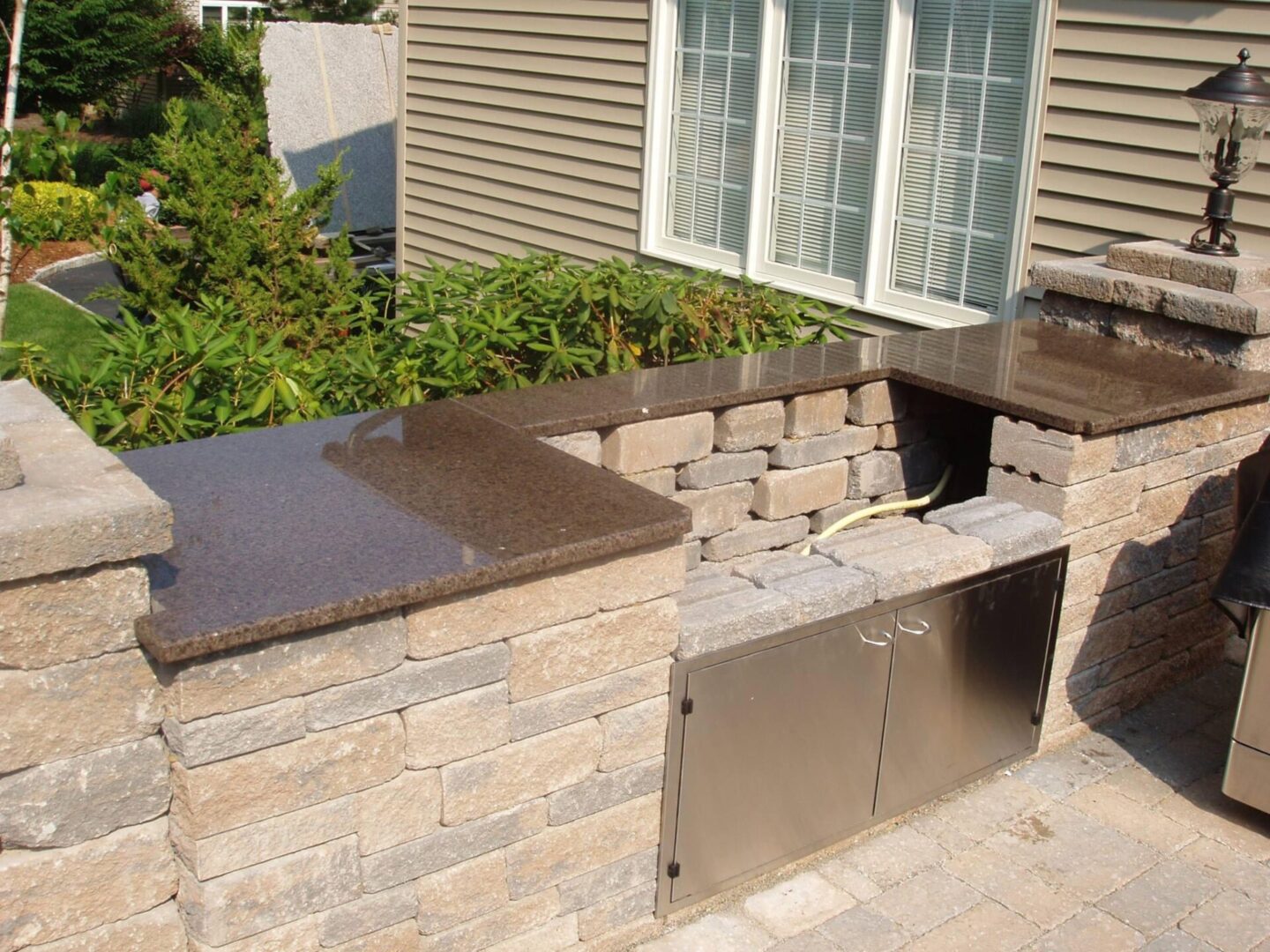 A brick patio with an outdoor grill and counter.