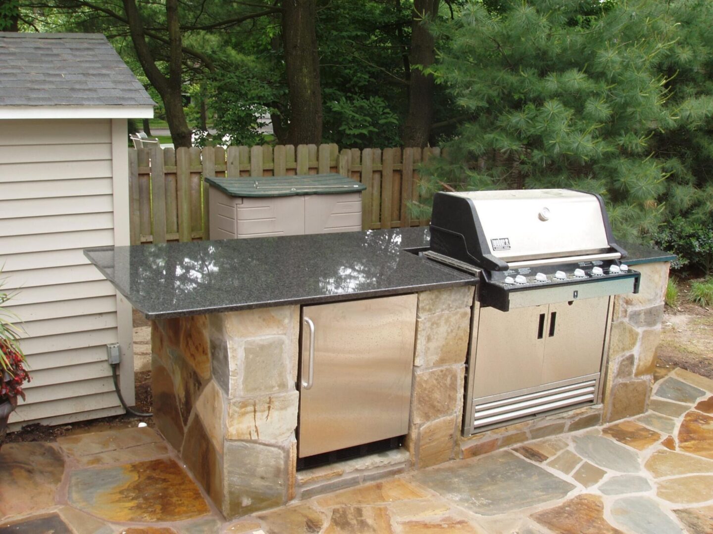 A grill and sink in the middle of an outdoor patio.