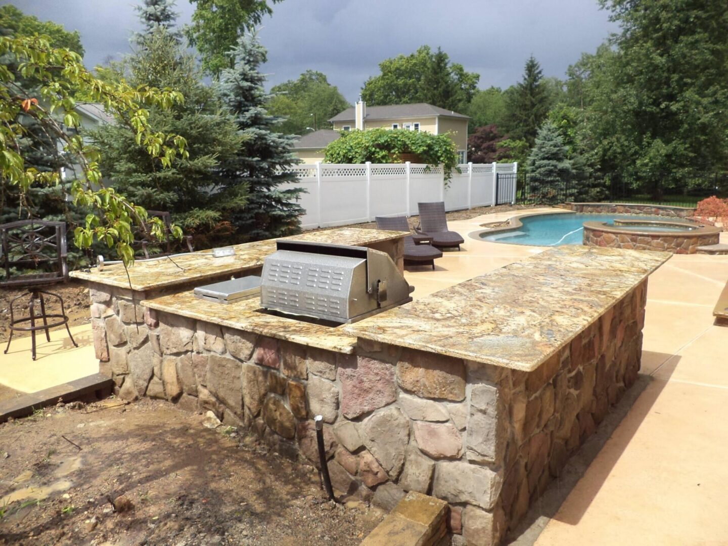 A stone wall with a grill and pool in the middle of it.