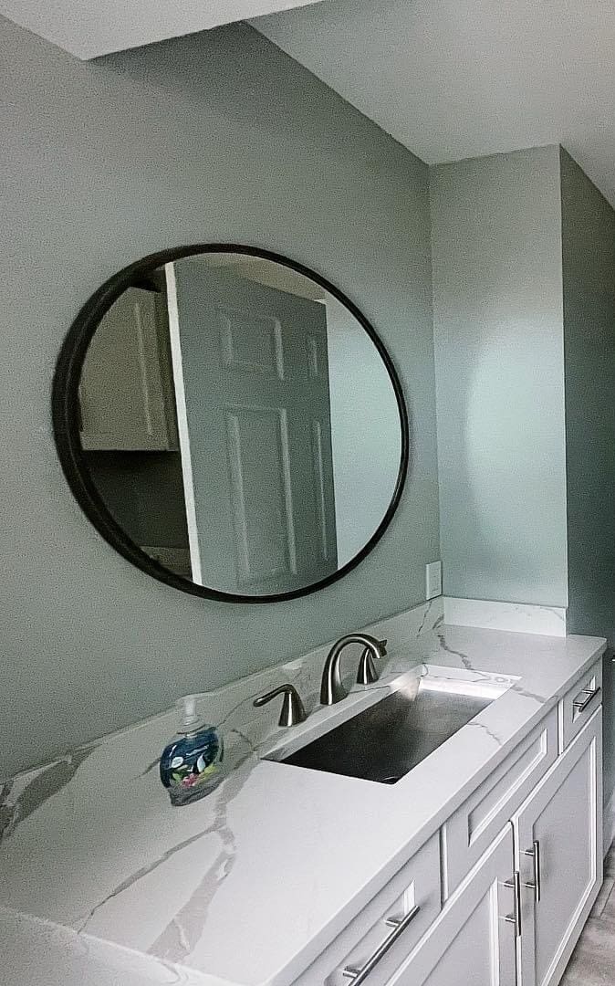 A bathroom with a sink and mirror in it