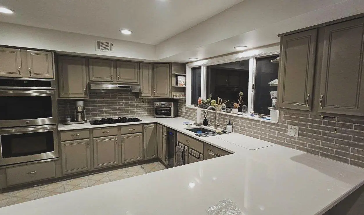 A kitchen with white counters and brown cabinets.