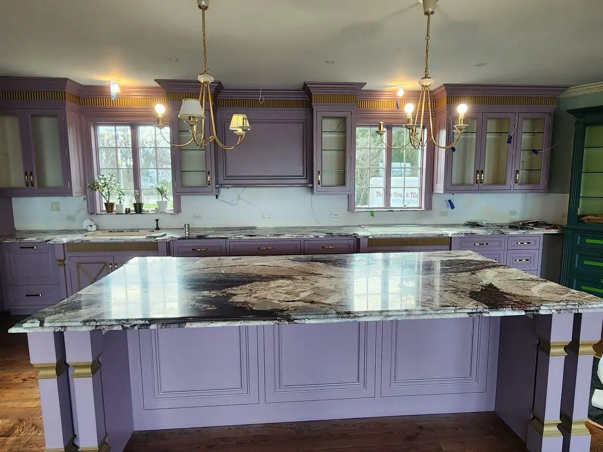 A kitchen with marble counter tops and purple cabinets.