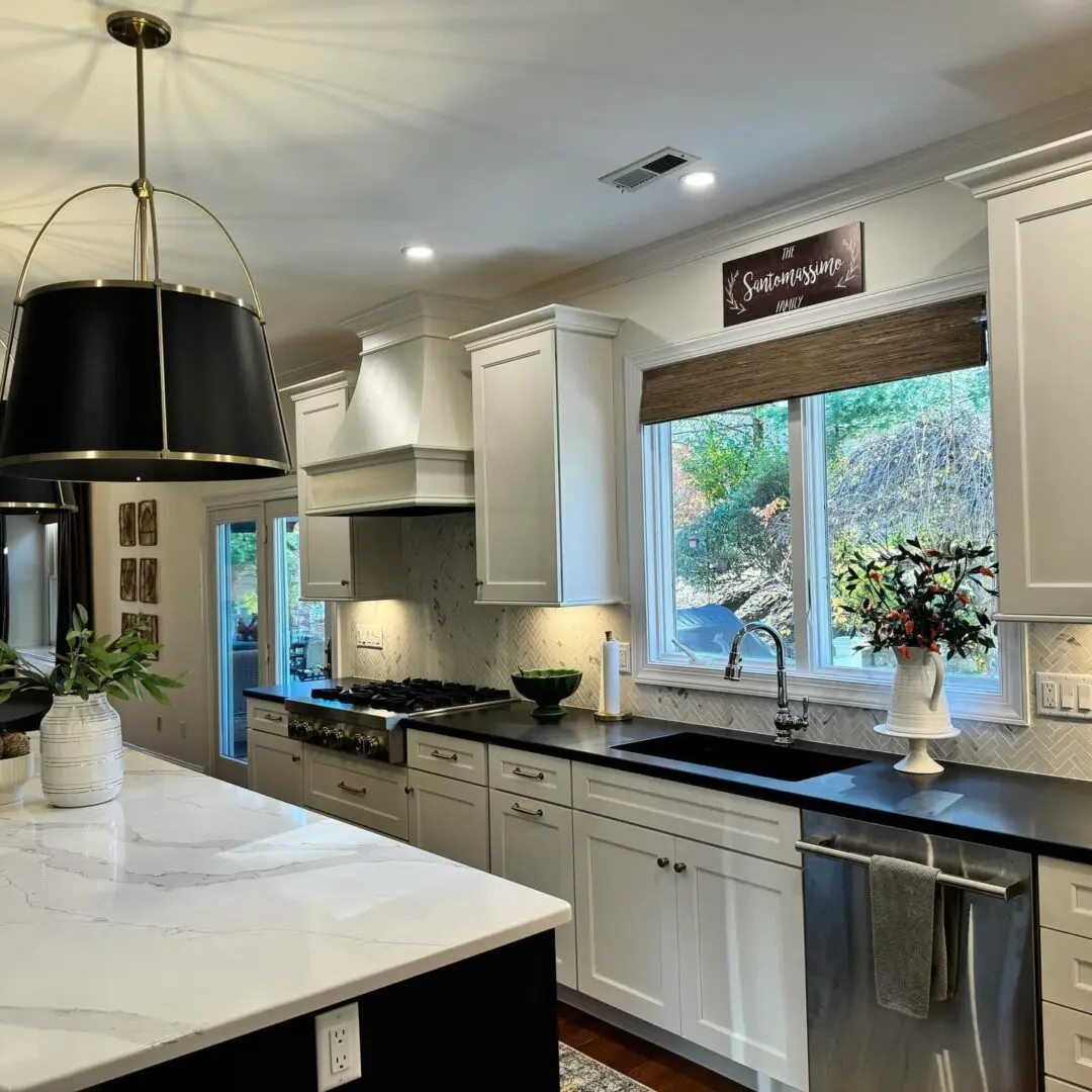 A kitchen with white cabinets and black counter tops.