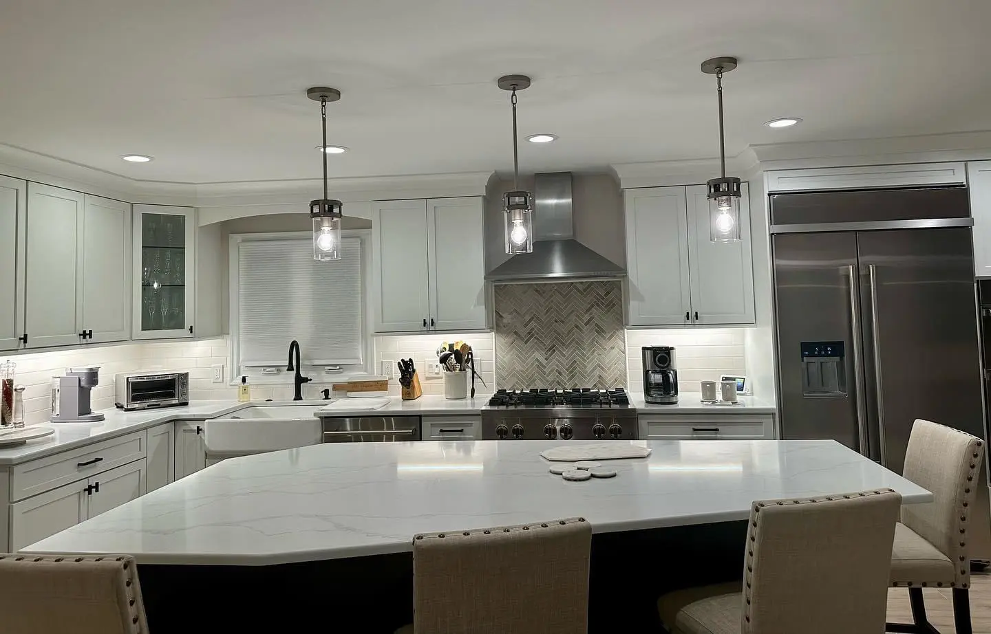 A kitchen with white cabinets and lights on the ceiling.