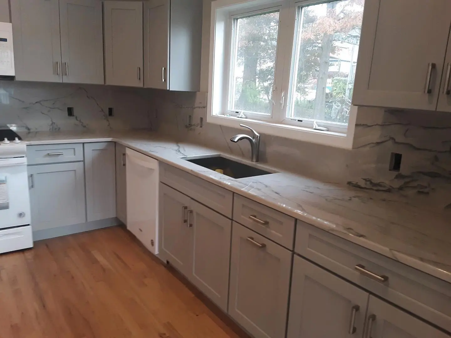 A kitchen with white cabinets and wooden floors.