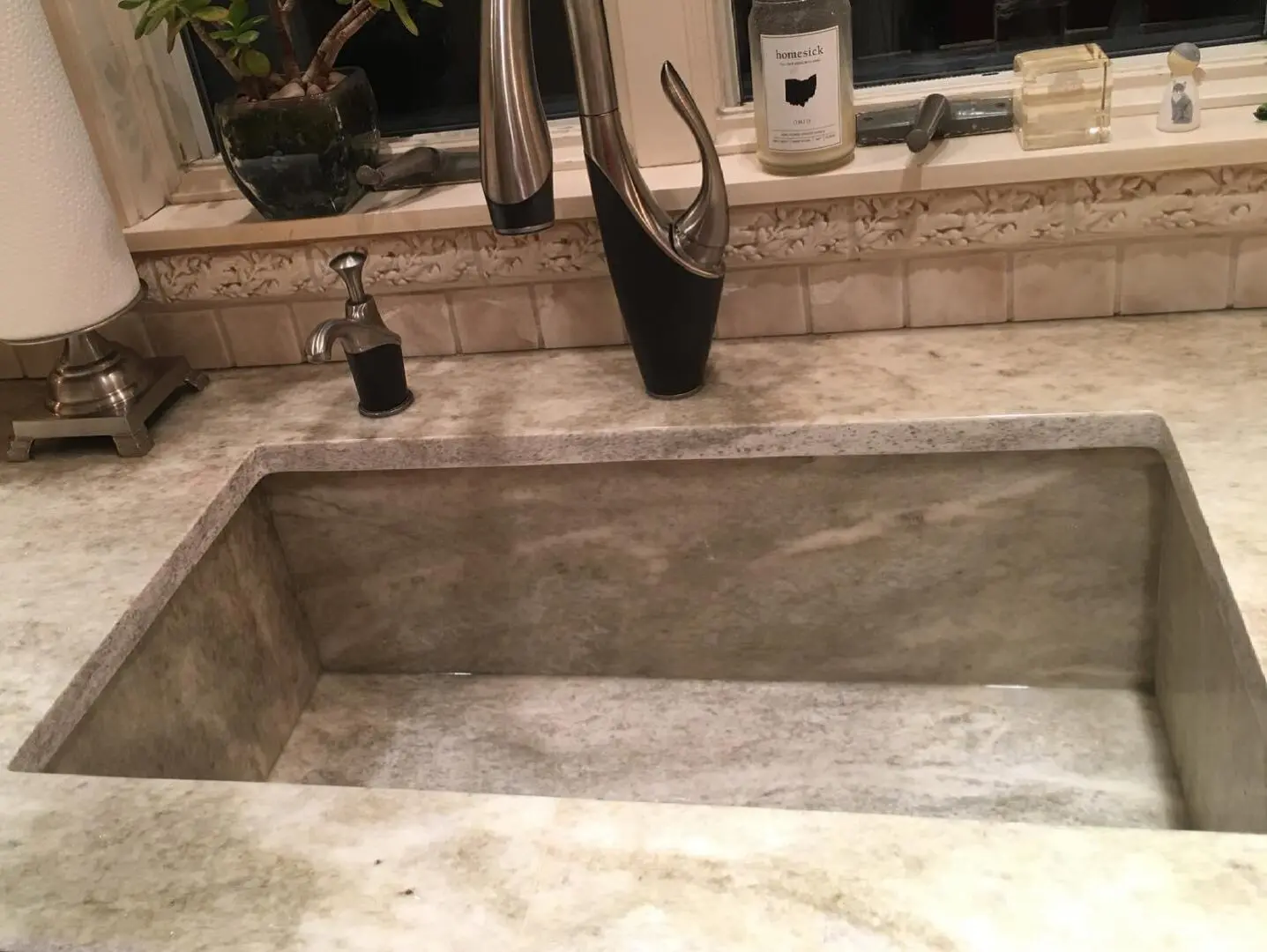 A sink with a faucet and mirror in the background.