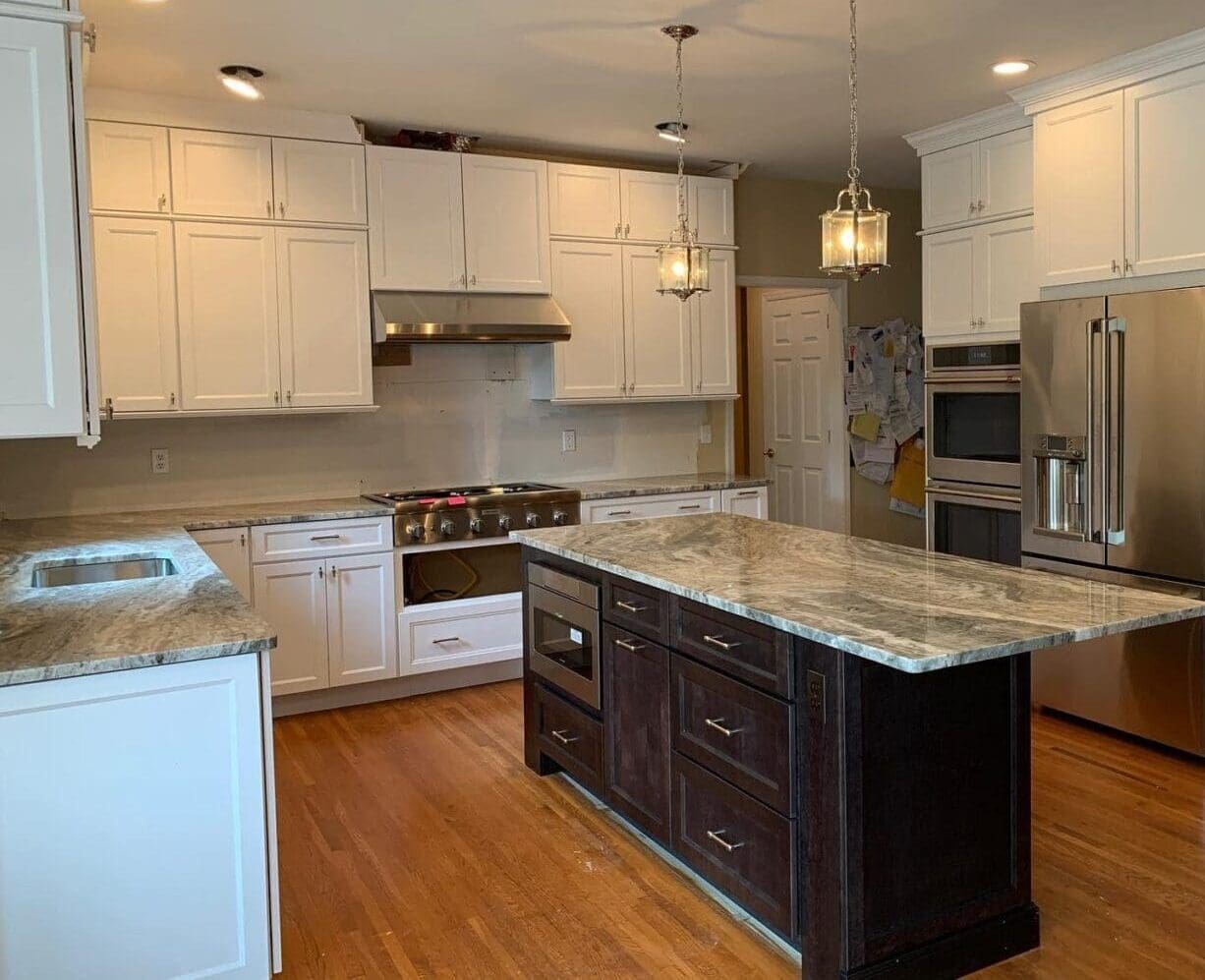 A kitchen with white cabinets and wood floors.