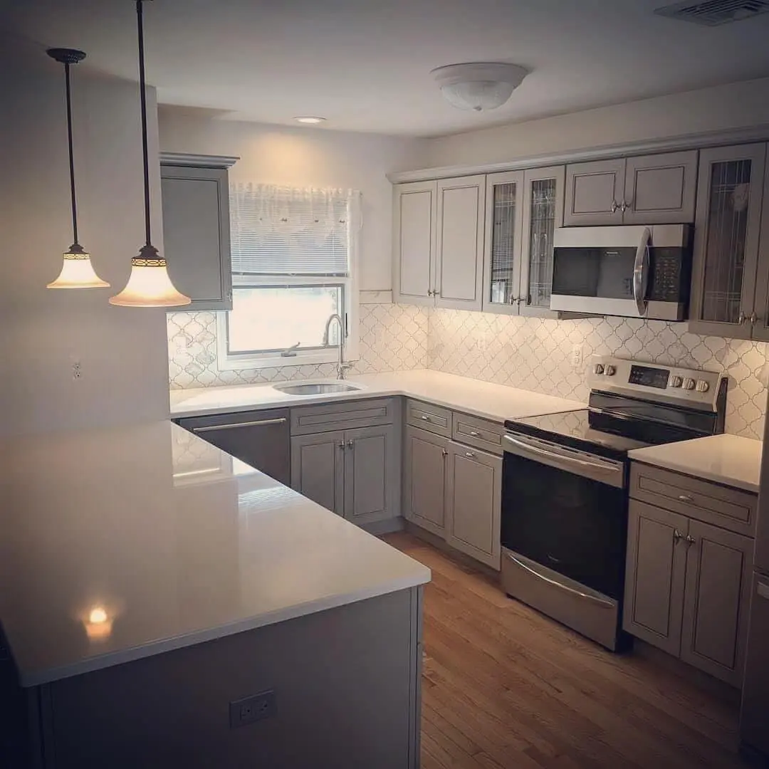 A kitchen with white cabinets and wooden floors.