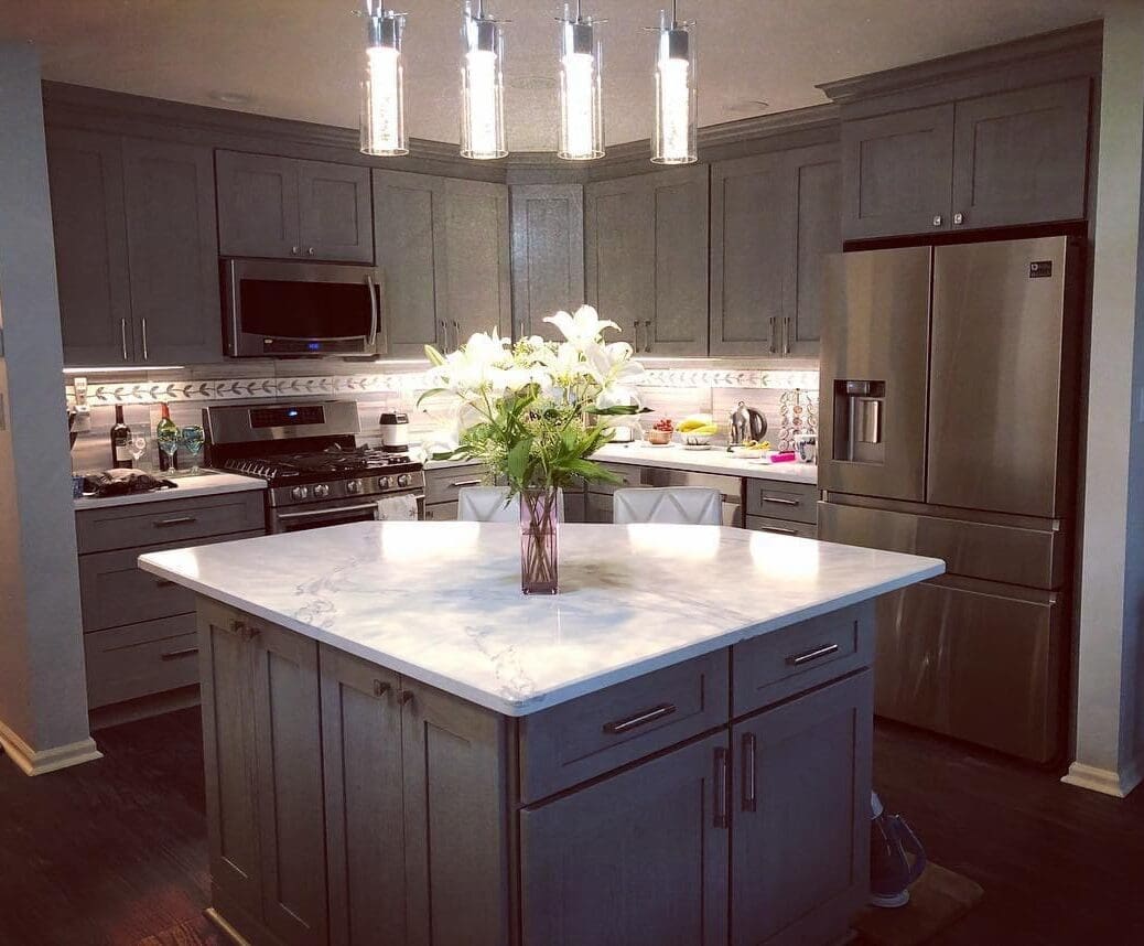 A kitchen with grey cabinets and white counter tops.