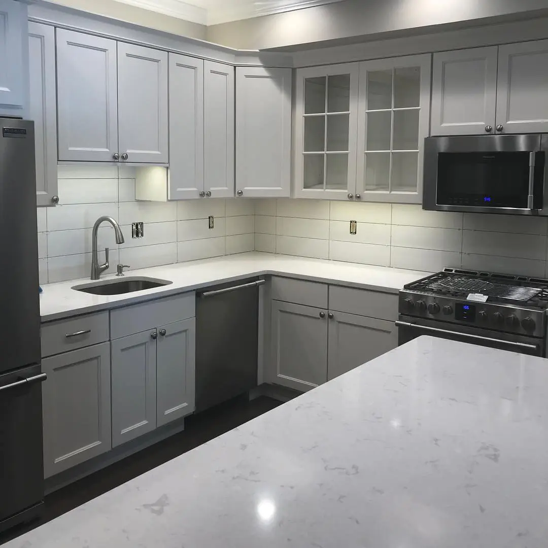 A kitchen with white cabinets and gray walls.