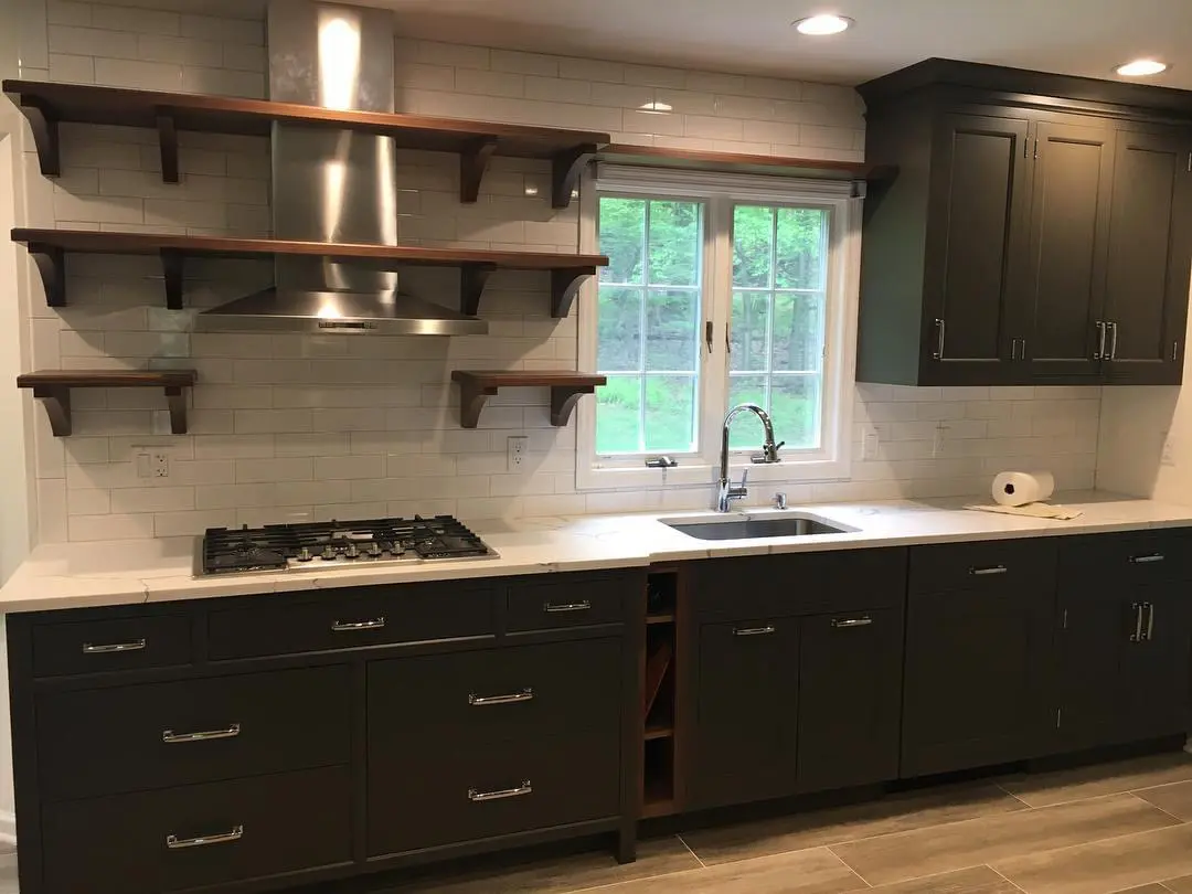 A kitchen with black cabinets and white counter tops.