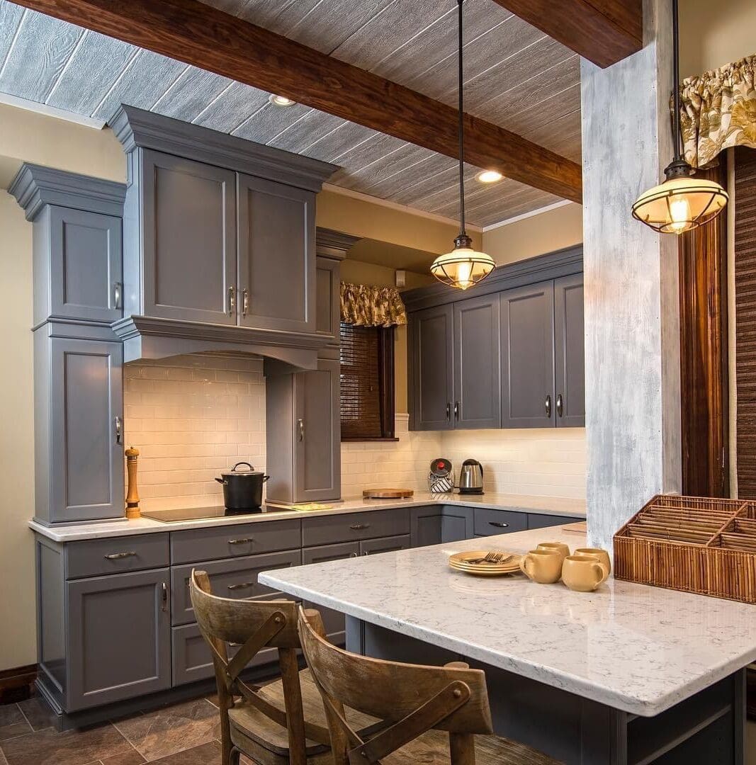 A kitchen with grey cabinets and white counter tops.