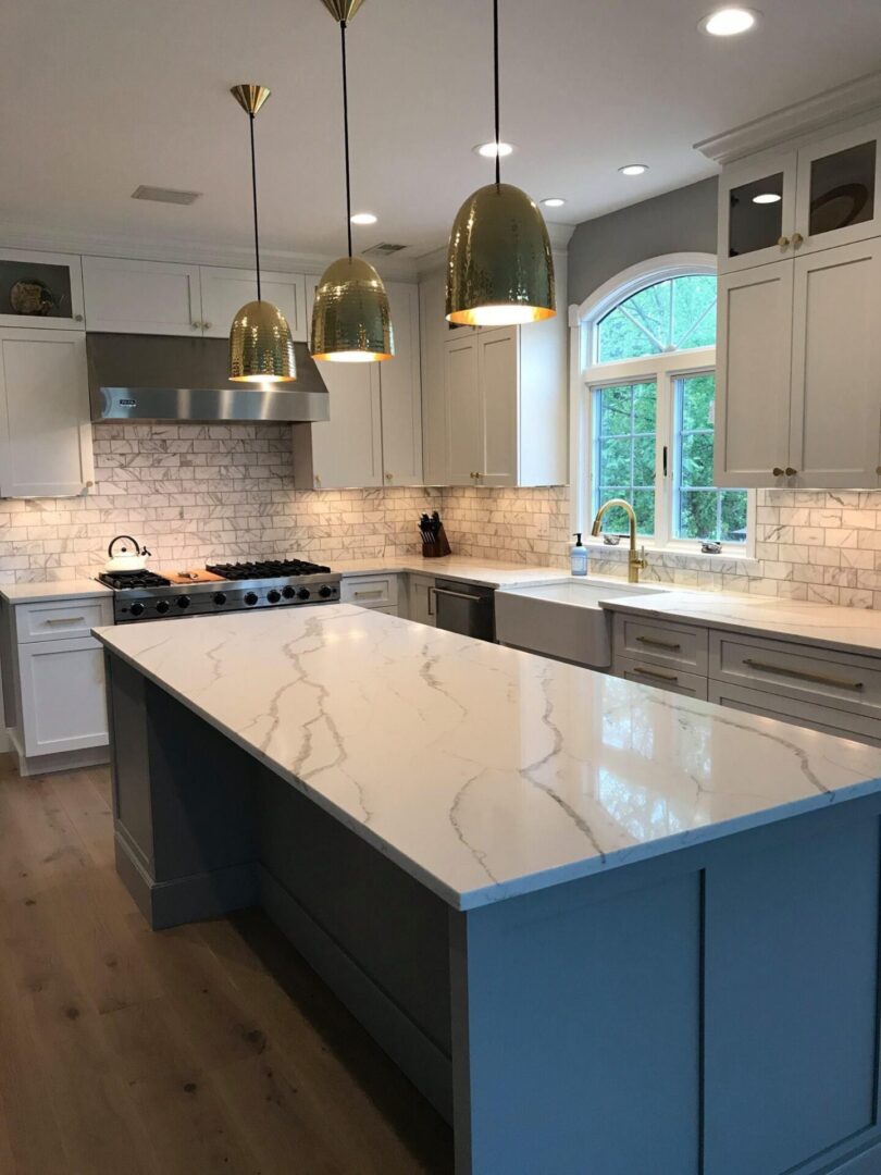 A kitchen with marble counter tops and white cabinets.