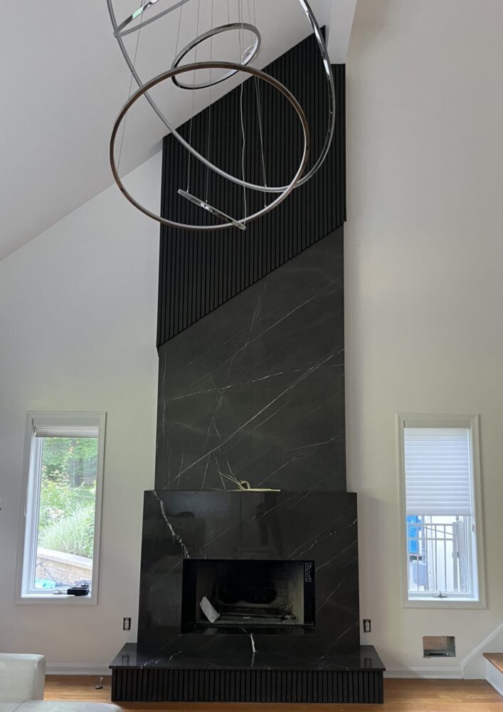 A fireplace with two windows and a black marble mantle.