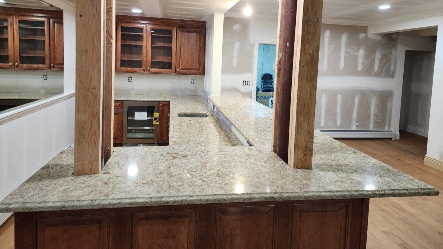 A kitchen with marble counter tops and wooden cabinets.