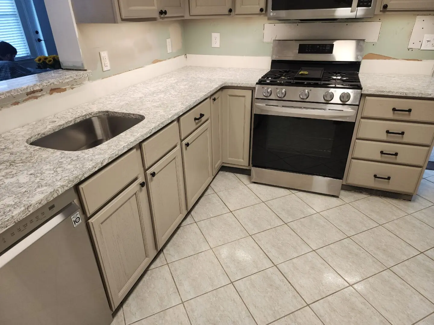 A kitchen with white tile floors and stainless steel appliances.