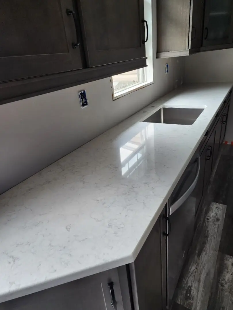 A kitchen counter with white marble and grey cabinets.