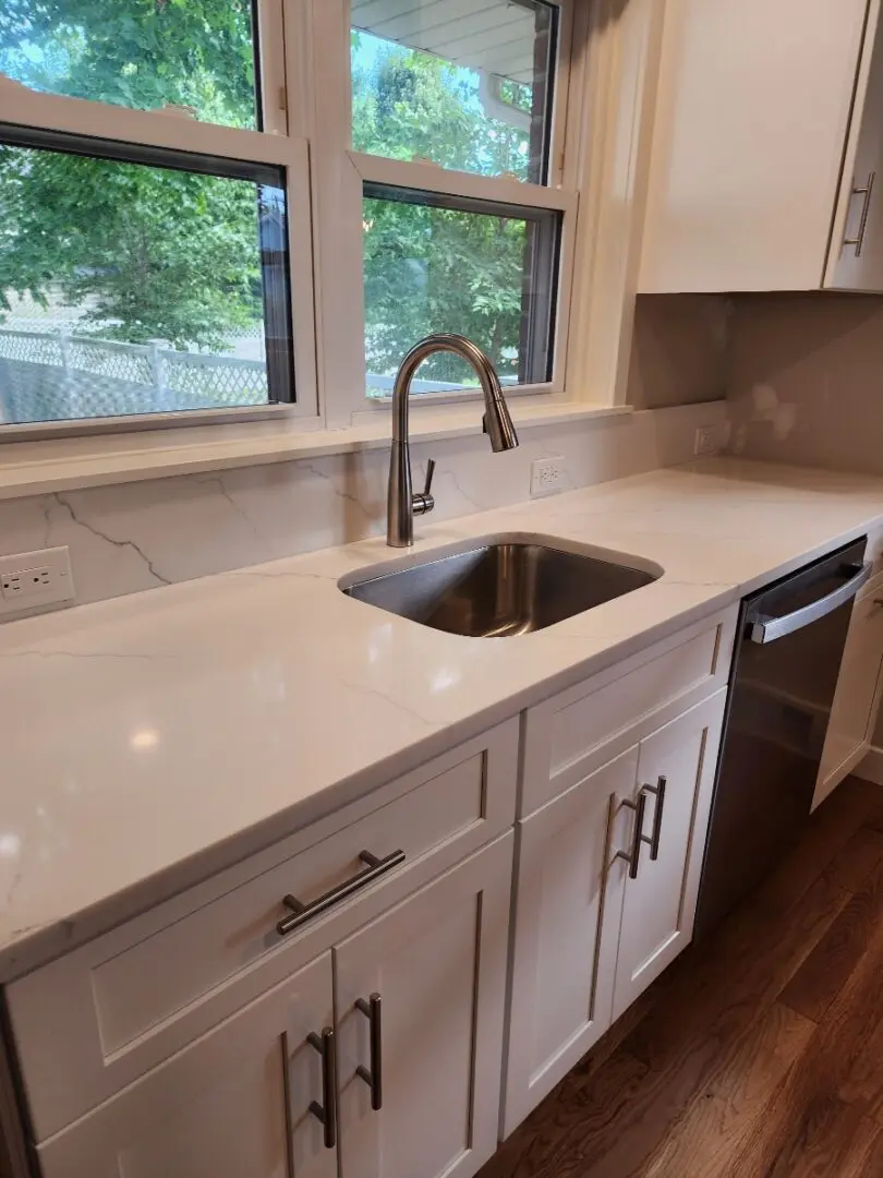 A kitchen with white cabinets and a sink.