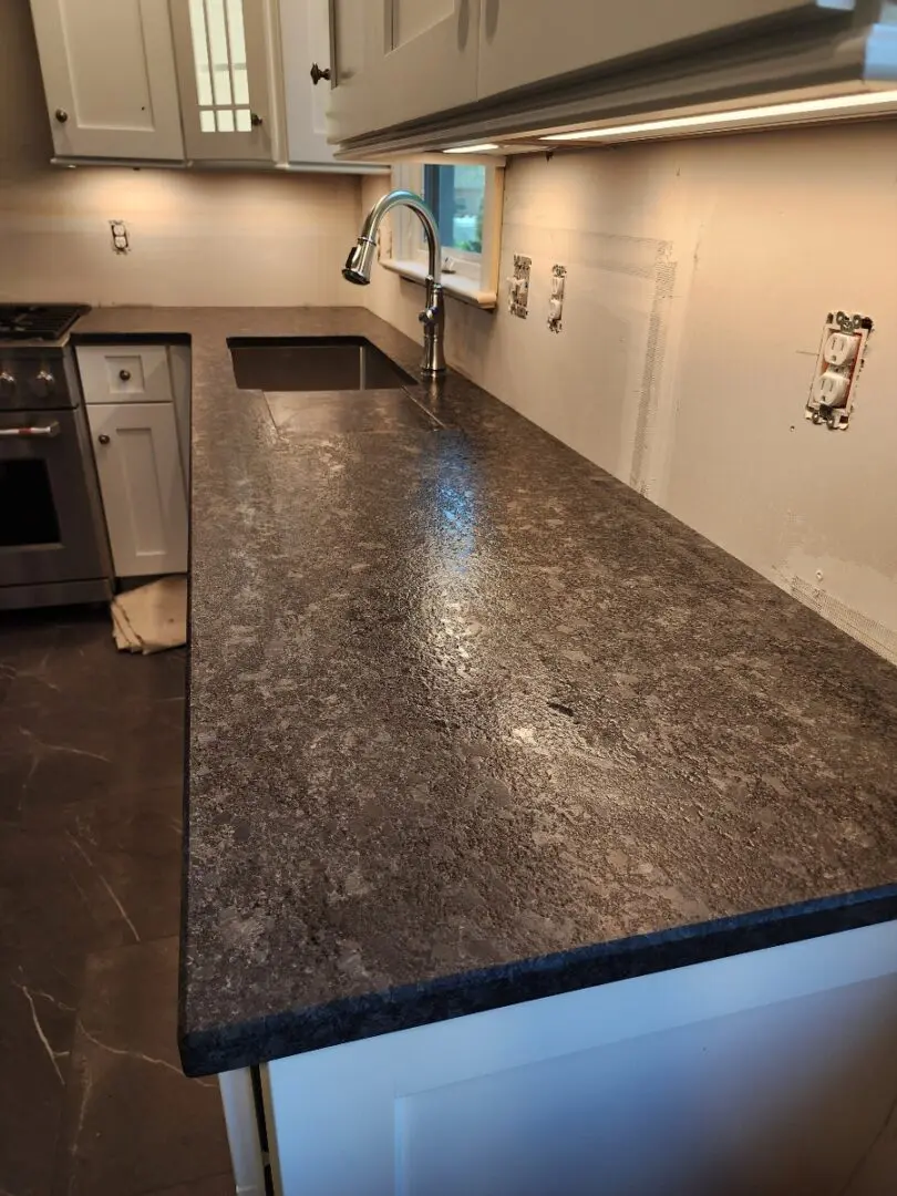 A kitchen with granite counter tops and white cabinets.