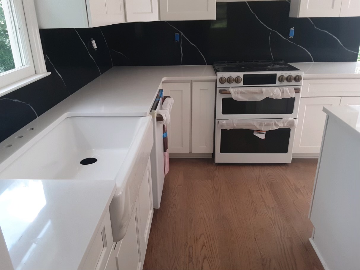 A kitchen with white cabinets and black walls.