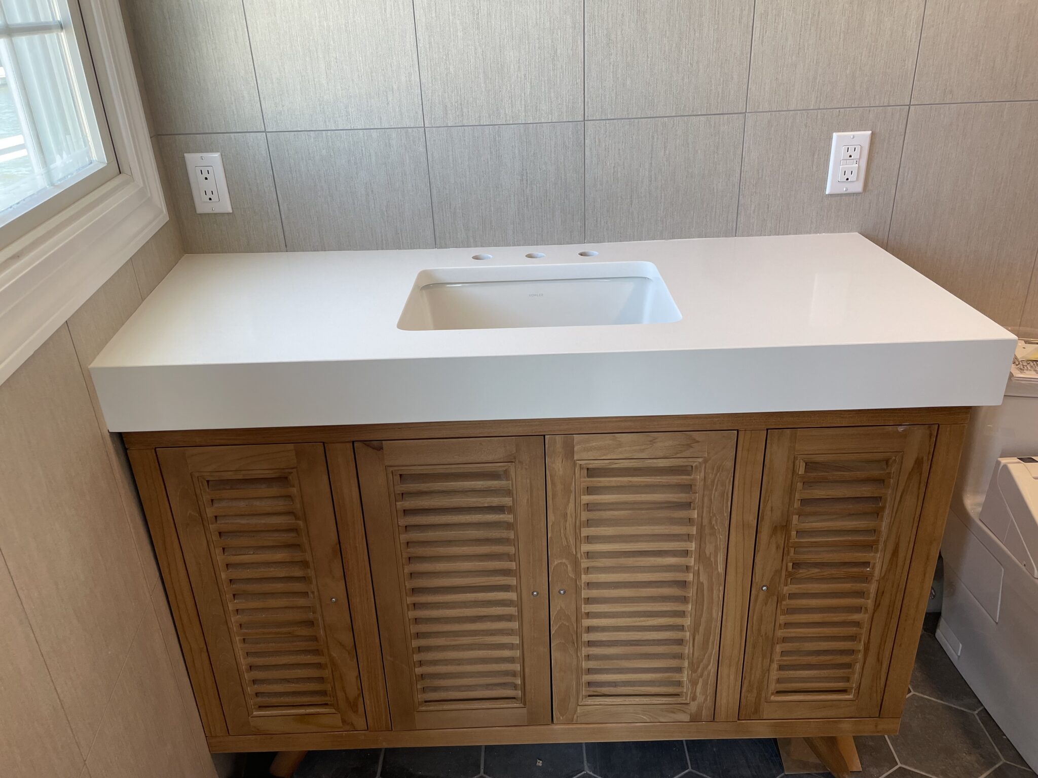 White countertop with wood cabinet sink.