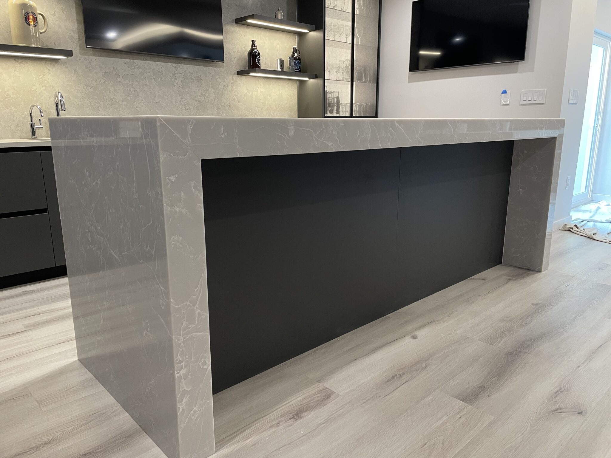 Grey kitchen island with black paneling.