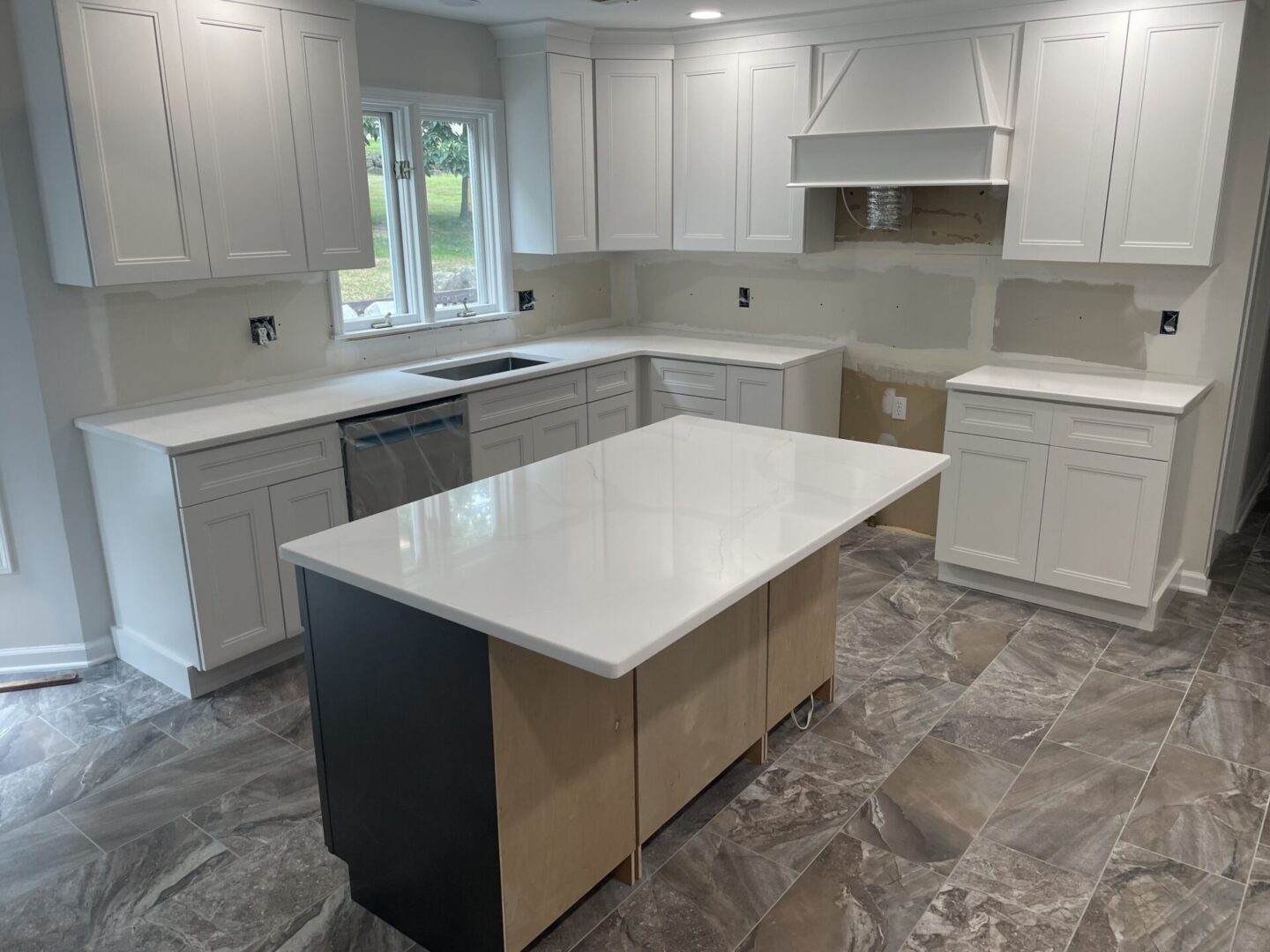 White kitchen with island and tile floor.