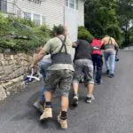 Men carrying a large sheet of drywall.