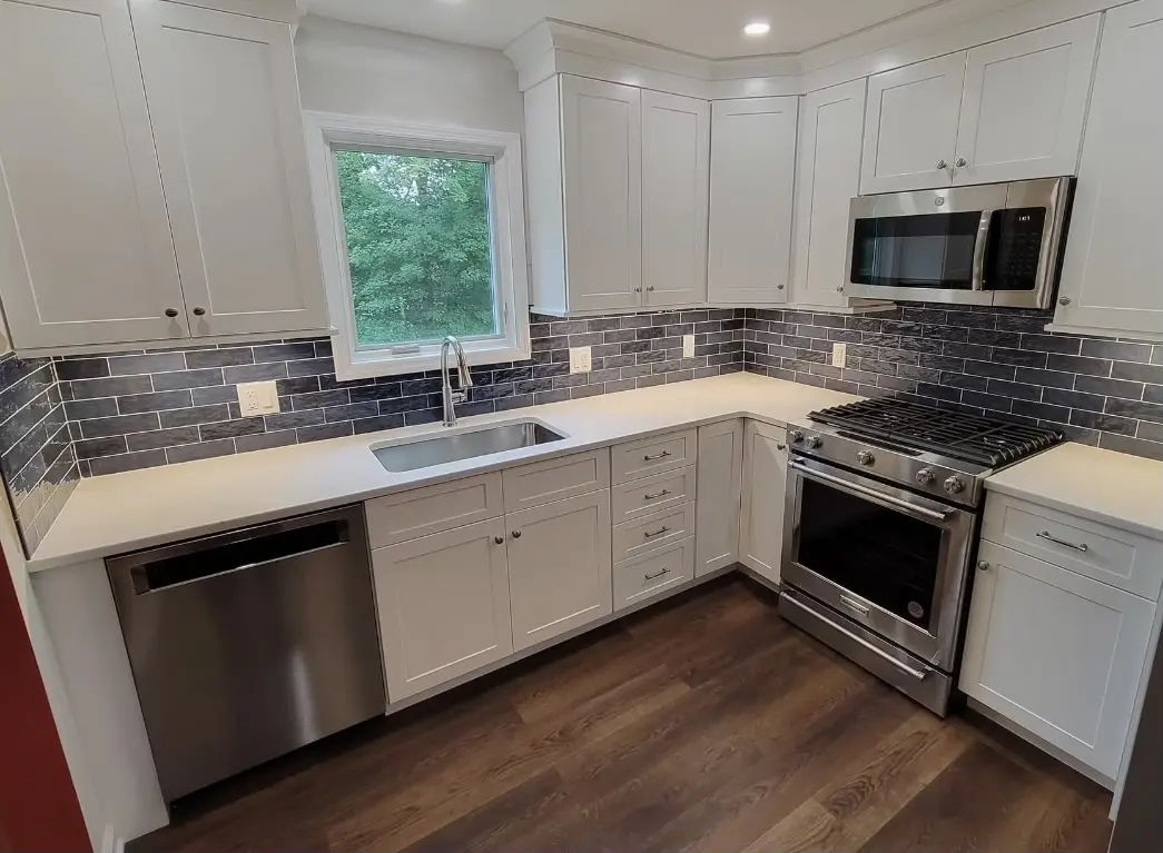 Modern kitchen with white cabinets and stainless steel appliances.