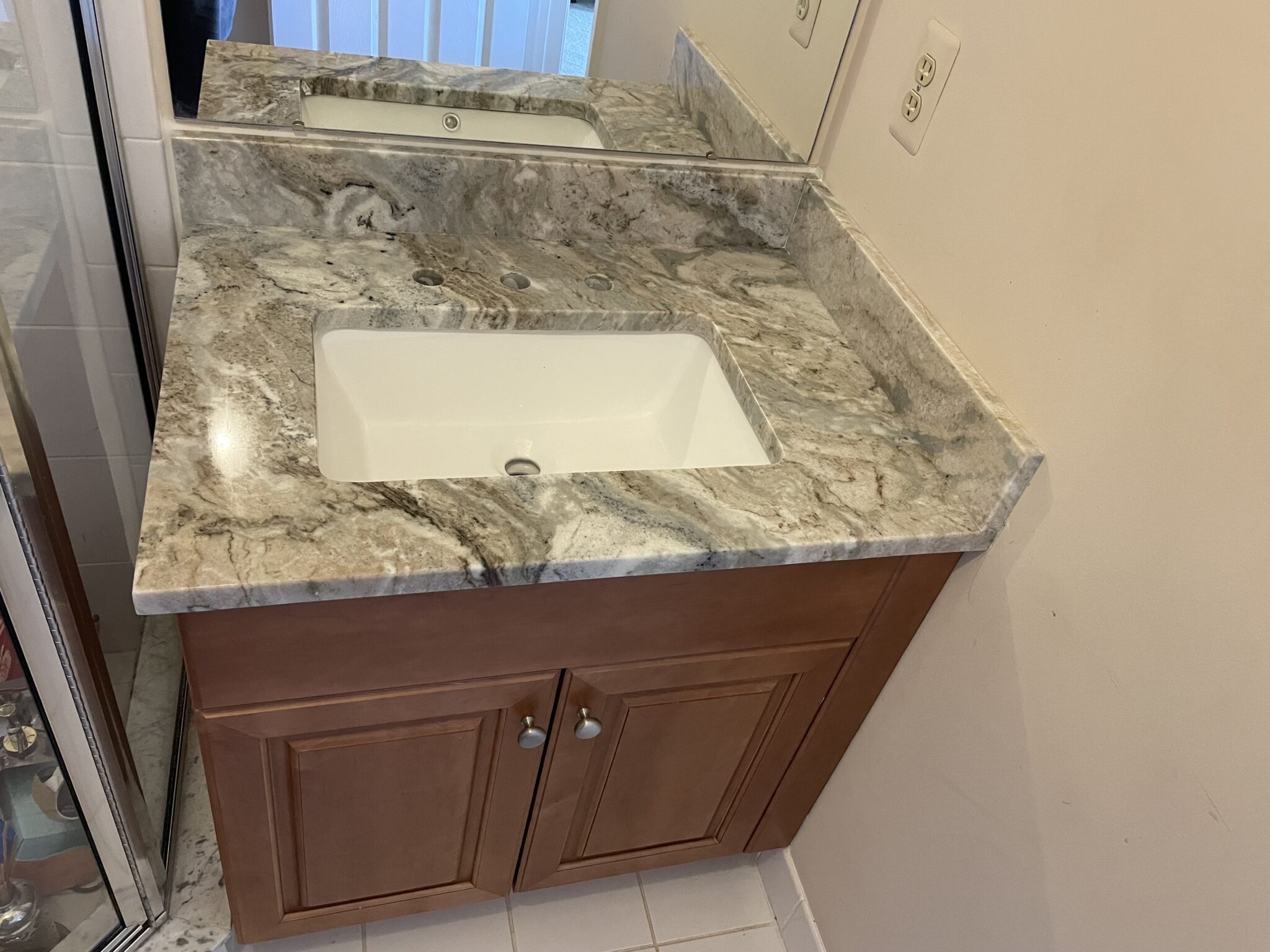 Bathroom vanity with granite countertop and sink.