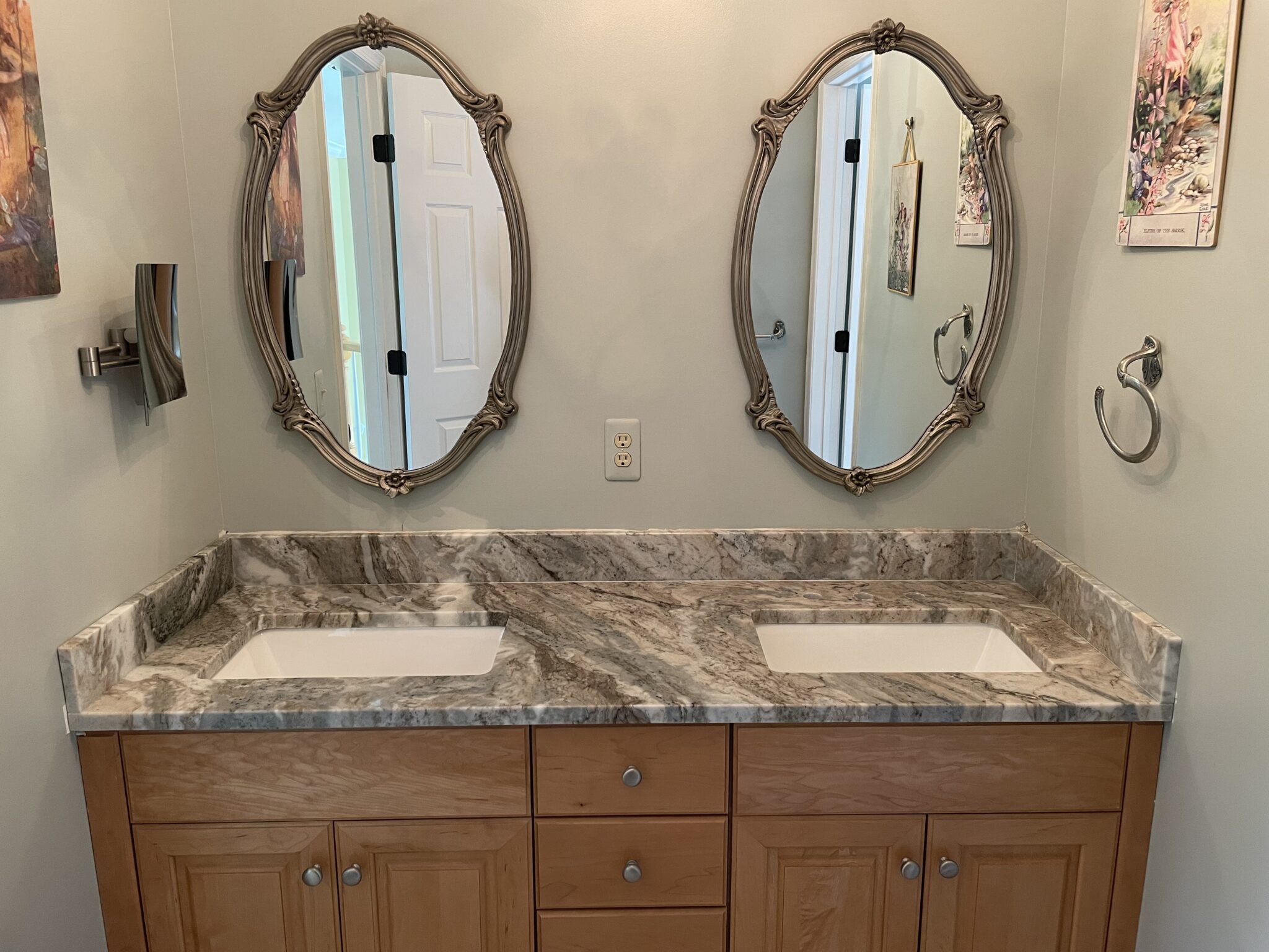 Double vanity with granite countertop and ornate mirrors.