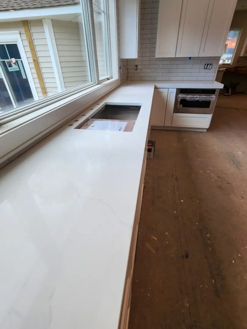 White kitchen countertop with sink and window.