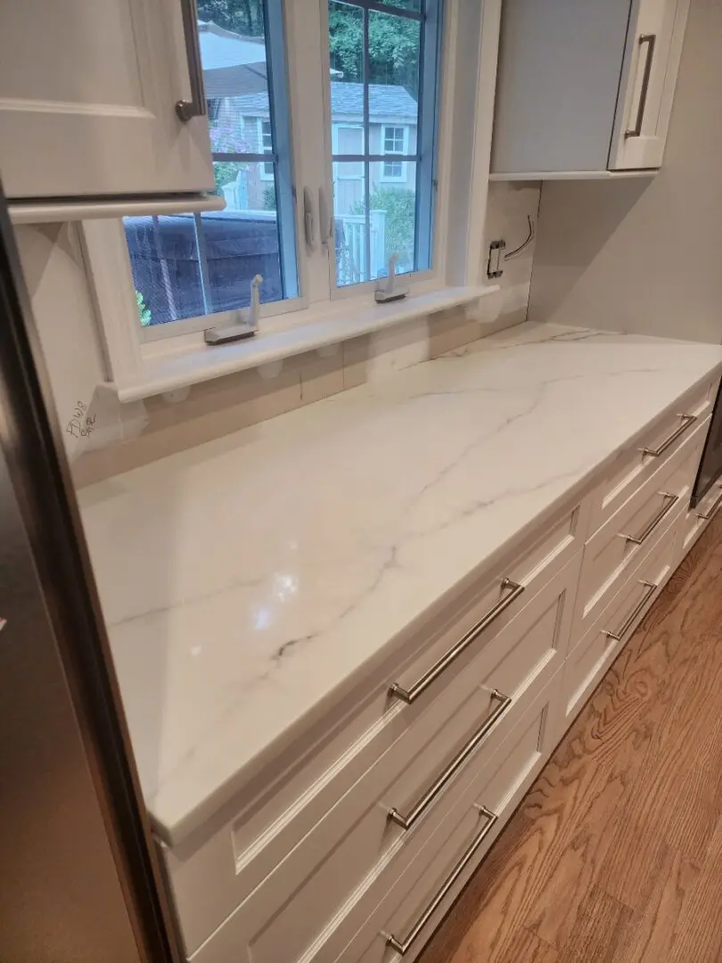 White marble countertop with white cabinets.