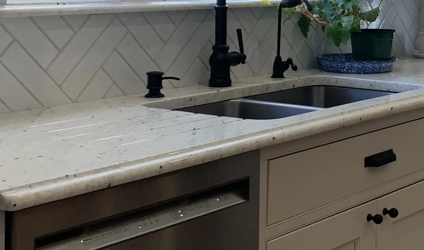 Kitchen sink with white tile backsplash.