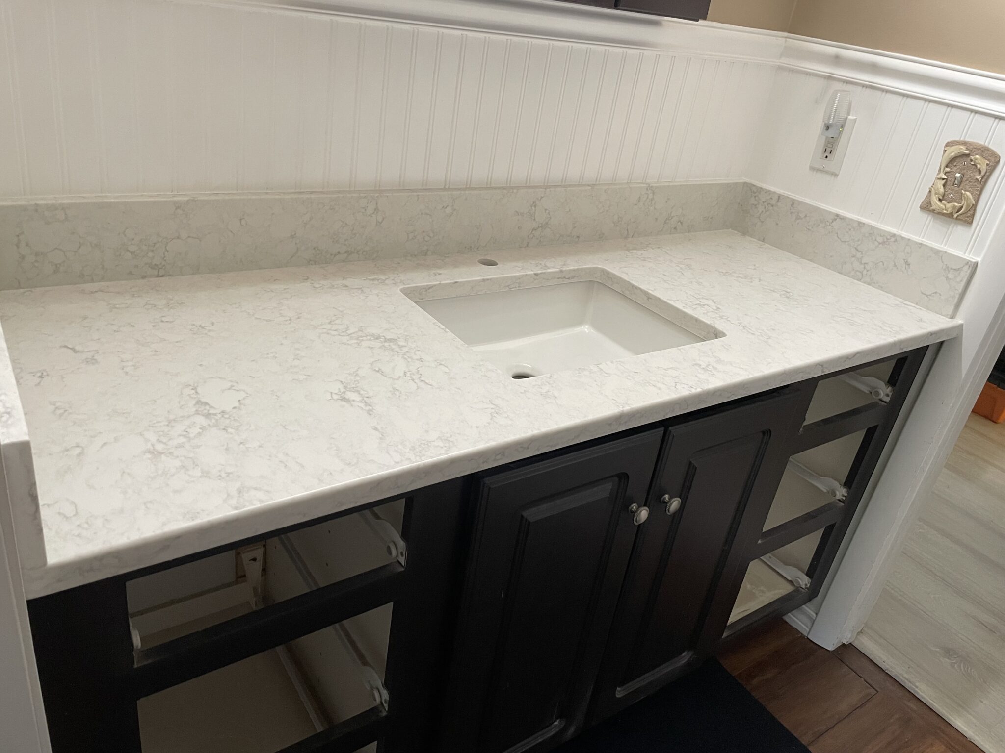 White countertop with sink and black cabinets.