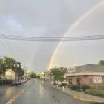 Double rainbow over a street with a bagel shop.