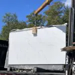 Large white marble slab being loaded onto truck.