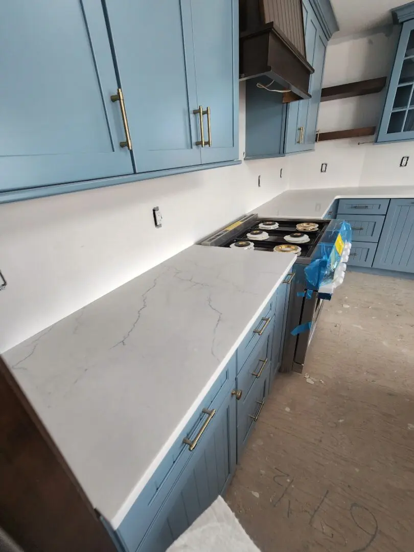 White quartz countertop in a blue kitchen.