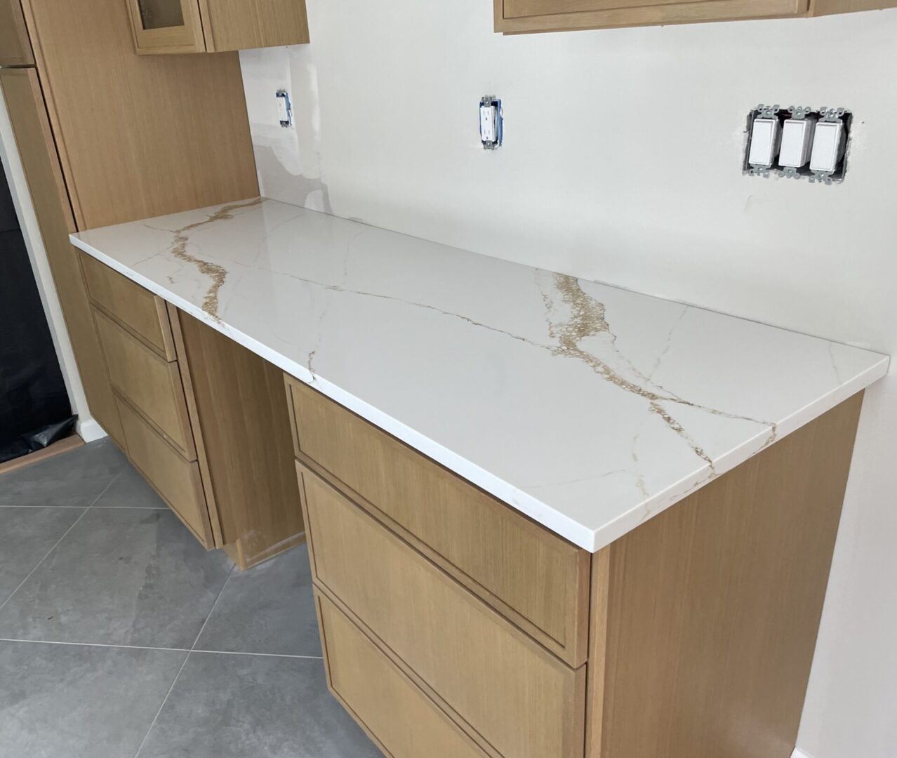 Quartz countertop on light wood cabinets.