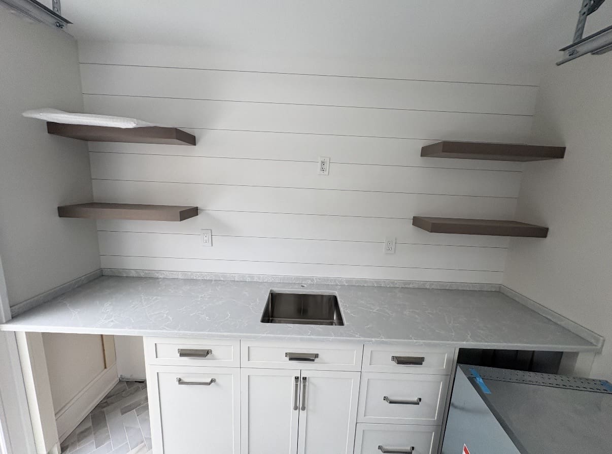 Long gray countertop with floating shelves and sink