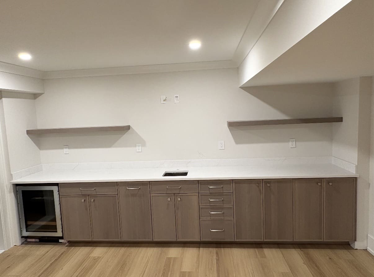 Wet bar with white marble countertop and cabinets
